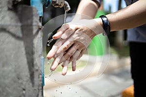 Close up,Asian people washing her hands,cleaning dirty hands from a faucet,tap water running weakly in public places in the city,