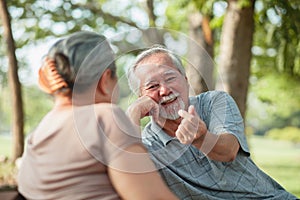 Close up, Asian senior couple having a good time while sitting outdoors in the park. Cheerful have a good time