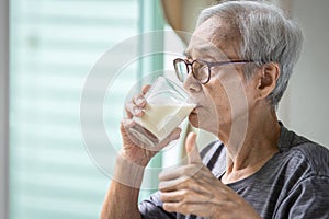 Close up,Asian senior woman drinking fresh milk from the glass,healthy elderly holding glass of milk,old people showing thumb up