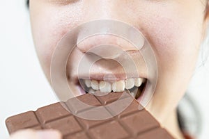 Close up,asian teenage girl eating tasty chocolate bar,deliciously sweet,enjoy the natural taste,smiling young woman holding