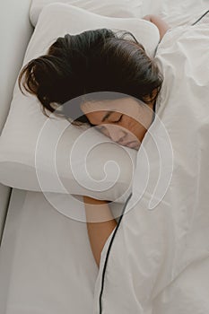 Close up of asian Thai woman closing eyes, sleeping on white bed in the morning in room apartment.