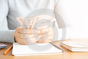 Close up of asian woman with calculator counting money.Woman calculate the spending at home