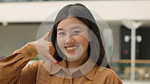 Close up Asian woman happy smiling japanese chinese korean girl businesswoman looking to camera doing phone gesture hey