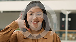 Close up Asian woman happy smiling japanese chinese korean girl businesswoman looking to camera doing phone gesture hey