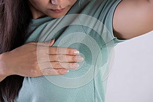Close-up asian woman with hyperhidrosis sweating. Young asia woman with sweat stain on her clothes against grey background. photo