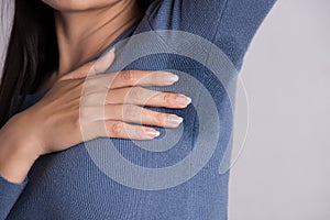 Close-up asian woman with hyperhidrosis sweating. Young asia woman with sweat stain on her clothes against grey background. photo