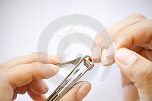 Close up Asian woman use steel tool cutting fingernails and cutted dirty nails on floor on white background