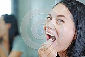 Close up Asian woman using dental floss to cleaning her teeth