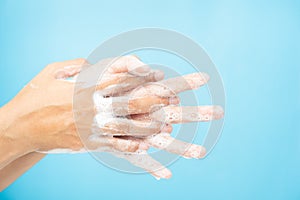 Close up of Asian women Cleaning hands with white soap bubbles on blue background. Hand washing demonstration for virus protection