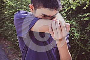 Close-up Asian young boy coughs in his elbow. Correct sneezing