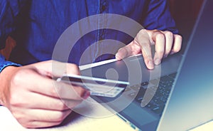Close up asian young man using laptop and holding credit card wi