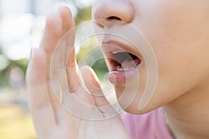 Close up,Asian young woman raised her hand near her mouth to whisper or speaks softly and gossip,child girl telling a secret or photo