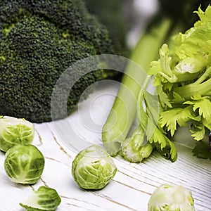 Close-up of assorted fresh vegetables on a white wooden table: cabbage, broccoli and Brussels sprouts and celery -organic products