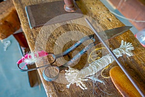 Close up of assorted materials, whool and scissors to work on loom manufacturing wool shawl clothing in Nepal