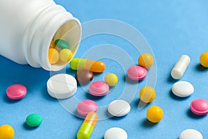 Close up of assorted medicine pills, tablets, capsules and bottle on blue background. Concept of medication treatment, health care