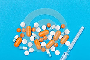 Close up of Assorted pharmaceutical medicine pills, tablets and syringe on blue background. Free space. Healthcare