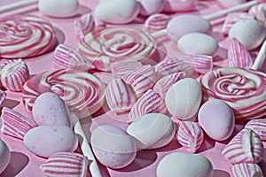 Close up of assortment of pink candies on pink background with selective focus