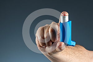 Close-up with an asthma inhaler in a male hand, asthmatic attack. The concept of treatment of bronchial asthma, cough, allergies,