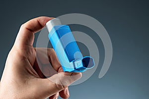 Close-up with an asthma inhaler in a male hand, asthmatic attack. The concept of treatment of bronchial asthma, cough, allergies,