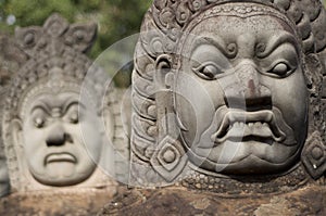 Close up of Asuras demons statues in a row at the Bayon Temple entrance gate