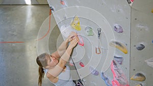 CLOSE UP: Athlete climber grips a pink crimp hold while trying to loop her rope