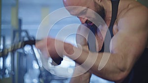 A close-up of an athlete and his muscles during an exercise with a battle rope.