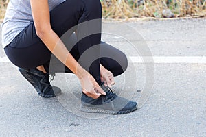 Close up Athlete running woman adjusting her running shoe.on the road,Runner woman traning in the morning.Walking for warm up her