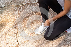 Close up Athlete running woman adjusting her running shoe.on the road,Runner woman traning in the morning.Walking for warm up her