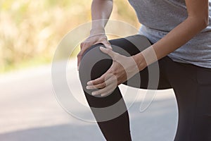 Close up Athlete running woman use hands hold on his knee while running in the morning.Knee injury on woman after traning for warm