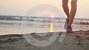 Close up of athletic man running on the beach at sunset through the sun in slowmotion. 1920x1080