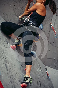 Close up of athletic woman practicing rock climbing on artificial wall indoors.