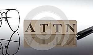 Close-up Of ATTN Wooden Blocks on the black background with glasses and pen