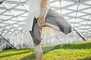 Close up of attractive athletic man practicing yoga and warming up outdoors.