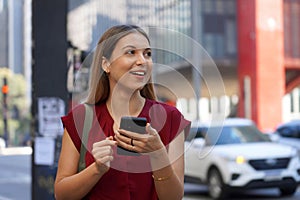 Close-up of attractive Brazilian business woman hail a vehicle using mobile app looking to the side on Paulista Avenue, Sao Paulo photo