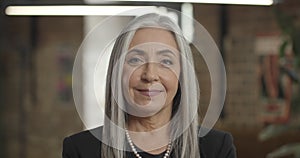 Close up of attractive elderly woman enterpreneur looking to camera and smiling. Middle aged confident businesswoman