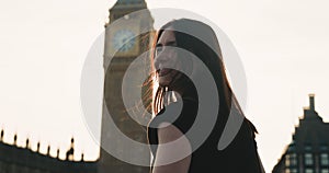 Close-up of attractive female looking at Big Ben and turning back to camera, smiling in bright sunlight