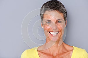 Close up attractive middle age woman smiling against gray background