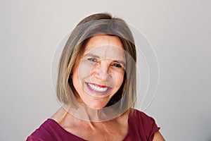 Close up attractive middle age woman smiling against gray wall