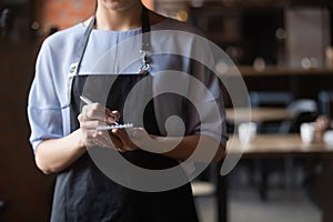 Close up attractive waitress ready to take order in coffeehouse