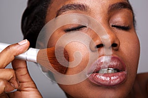 Close up attractive woman applying makeup with brush for beautiful complexion