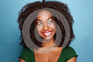 Close up attractive young african woman with curly hair looking away on blue background