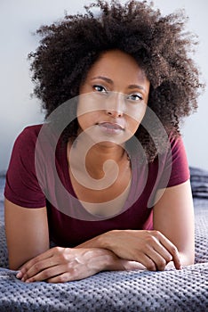 Close up attractive young black woman with curly hair lying on floor at home