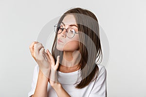 Close-up of attractive young brunette woman in glasses looking at fingernails after beauty salon