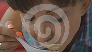 Close-up of attractive young caucasian woman eating soup with molluscs on open terrace of japanese restaurant.