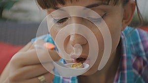 Close-up of attractive young caucasian woman eating soup with mussels on open terrace of japanese restaurant.