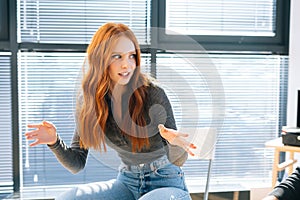 Close-up of attractive young redhead businesswoman talking and discussing new ideas with creative business team