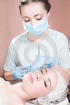 Close-up Attractive young woman gets anti-aging face injections. She lies calmly in a clinic or salon. An experienced