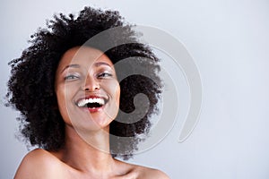 Close up attractive young woman with naked shoulders laughing on gray background