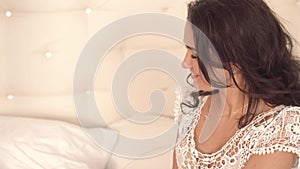 Close-up of attractive young woman waking up as her husband brings coffee in bed to her