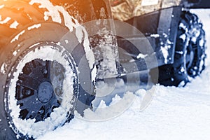 Close-up ATV 4wd quad bike in forest at winter. 4wd all-terreain vehicle stand in heavy snow with deep wheel track. Seasonal